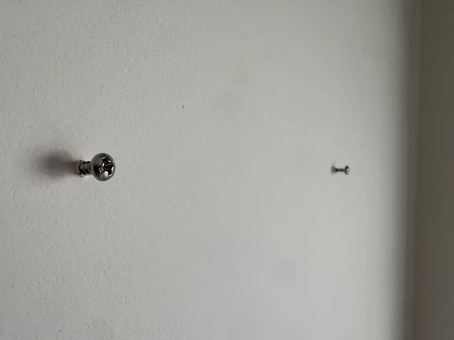Dos tornillos colocados en la pared para colgar el diorama